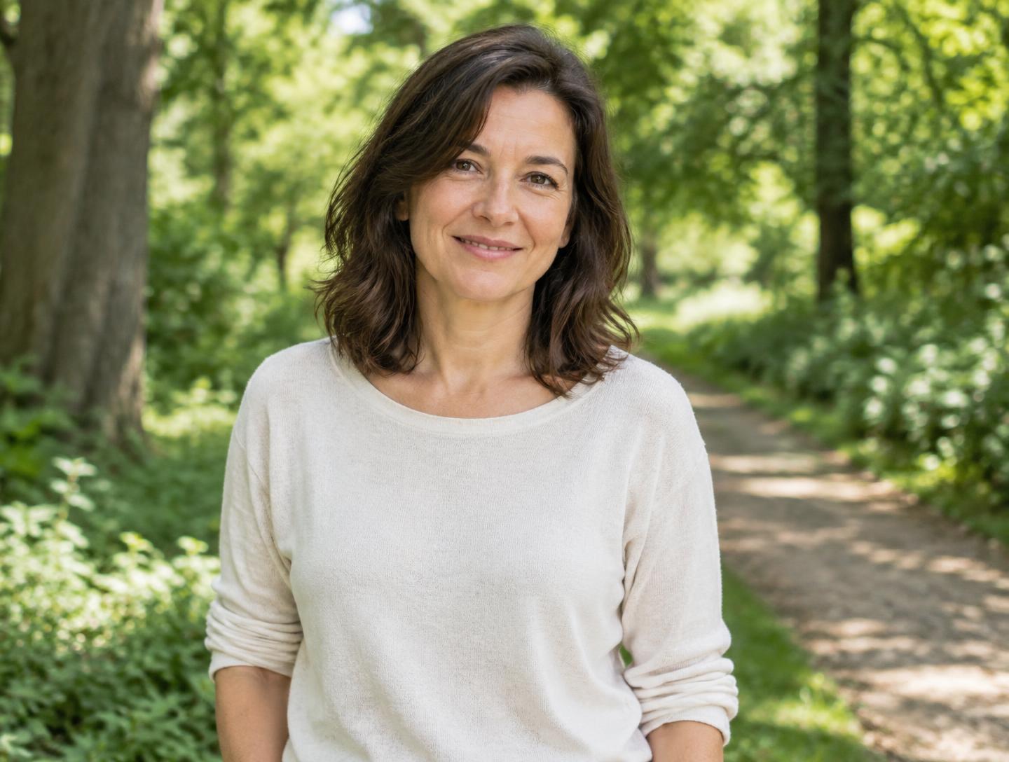A woman in her early forties outdoors on a leafy park path